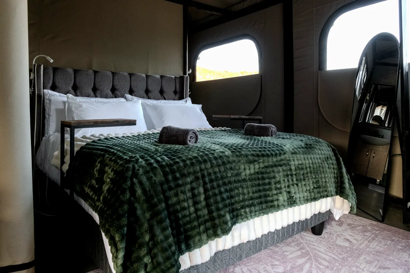 Extra length king bed dressed in white linen with a deep green throw, inside the tent